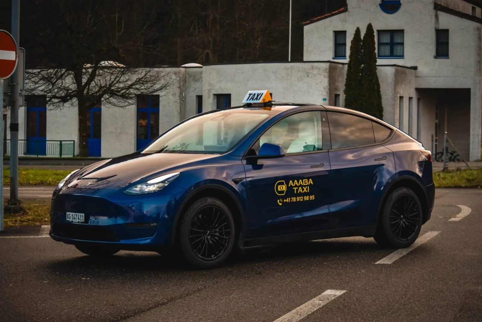 Blaues Tesla Model Y mit Aaaba Taxi Beschriftung
